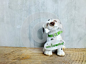 Ceramic dog with welcome sign on wooden background