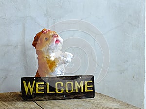 Ceramic dog with welcome sign on wooden background