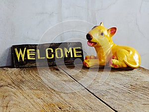 Ceramic dog with welcome sign on wooden background