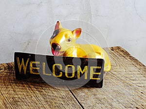 Ceramic dog with welcome sign on wooden background