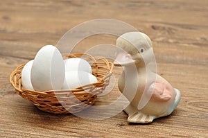 A ceramic duck with a basket filled with white easter eggs