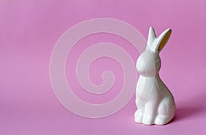 Ceramic Easter bunny on pink background, Easter minimalism concept with copy space