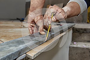 Ceramic floor tiles - man hands marking tile to be cut, closeup