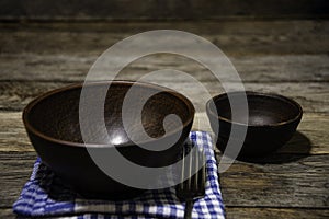 Ceramic folk bowl on a napkin, a fork and a small bowl on the table. Lunch is coming.