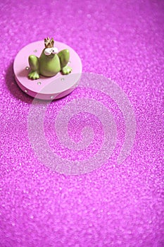 Ceramic frog prince on pink glitter background