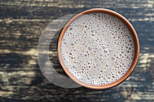 Ceramic glass of chocolate milkshake on wooden background. Top view, copy space