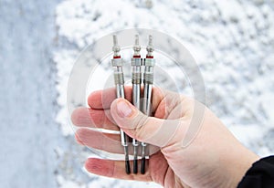 Ceramic glow plugs for a diesel engine in a hand against a background of snow in winter. Makes it easier to start the