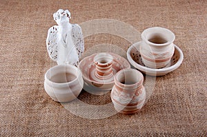 Ceramic greybeard, angel and candlestick on sackcloth background