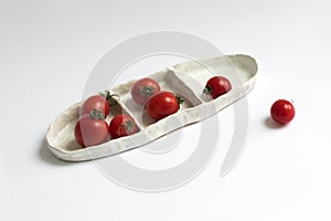 Ceramic handmade utensils with red tomatoes on a white background