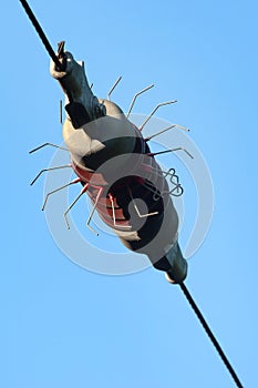 Ceramic insulator on a powerline against blue sky background