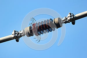 Ceramic insulator on a powerline against blue sky background