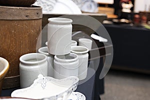 ceramic jars for bulk products on an old brown chest of drawers at an antique market