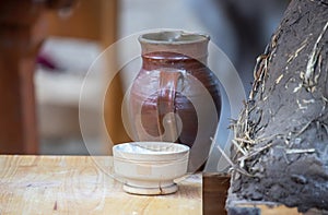 Ceramic jug, bowl with flour and medieval clay oven for baking bread close-up, dishes on a wooden table, still life