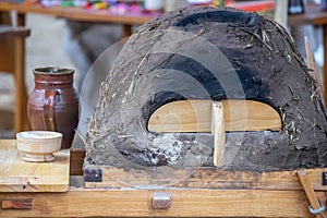 Ceramic jug, bowl with flour and medieval clay oven for baking bread close-up, dishes on a wooden table, still life