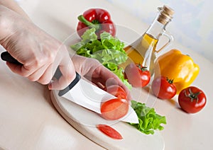 Ceramic knife in hand cutting tomatoes for salad