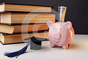 Ceramic moneybox with stack of books and cap. College, graduate, education, savings concept