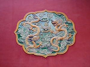 Ceramic mosaic depicting two dragons on the red wall of a building, Forbidden City, Beijing