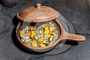 Ceramic pan with open lid that lets you see a boiling meal