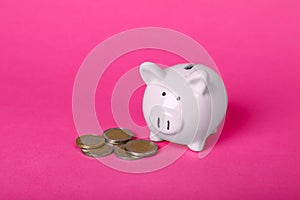 Ceramic piggy bank and coins on pink background. Financial savings