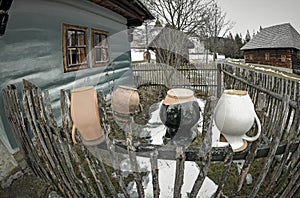 Ceramic pitcher on fence in village