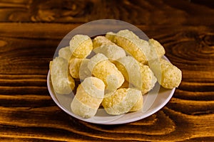 Ceramic plate with corn sticks on wooden table