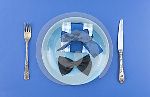 Ceramic plate with a cutlery and gift box on the blue paper background