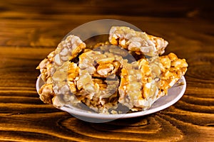 Ceramic plate with peanut brittles on wooden table.