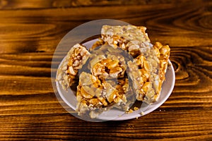 Ceramic plate with peanut brittles on wooden table.