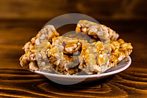 Ceramic plate with peanut brittles on wooden table.