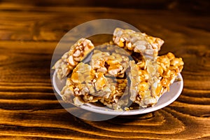 Ceramic plate with peanut brittles on wooden table