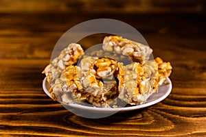 Ceramic plate with peanut brittles on wooden table