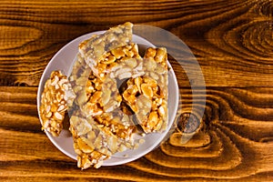 Ceramic plate with peanut brittles on wooden table. Top view