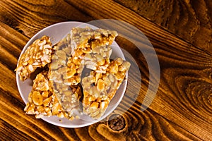 Ceramic plate with peanut brittles on wooden table. Top view