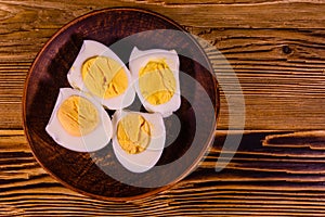 Ceramic plate with peeled boiled eggs on wooden table. Top view
