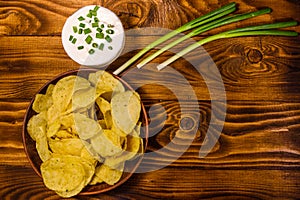 Ceramic plate with potato chips and glass bowl with sour cream o