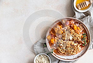 Ceramic plate with tasty plum crumble dessert served with vanilla ice cream and herbs. Light background. Top view