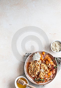 Ceramic plate with tasty plum crumble dessert served with vanilla ice cream and herbs. Top view