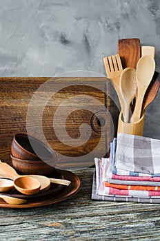 Ceramic plates, wooden or bamboo cutlery, vintage cutting board and towels in interior of kitchen