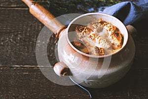 Ceramic pot with onion soup on the wooden table horizontal