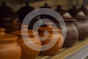 Ceramic pots for baking are on the shelf in a row to bake
