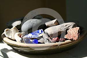 Ceramic pottery dish filled with china, marbles, rocks shells berries