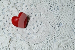 Ceramic red heart on white lace knitted fabric. Crochet Favorite hobby, Valentine.