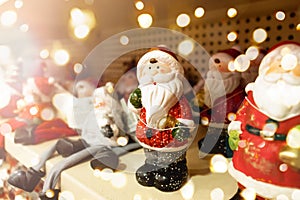 ceramic santa claus figurines stand on a store shelf. Selective focus. Defocus lights.