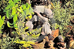 Ceramic sculptures of children in the garden, water running from the tap into a wooden tub, lush greenery,