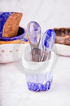 Ceramic set on a white marble background. White, blue and brown colors. Cups, spoons, bowls. Handmade