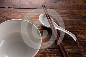 Ceramic spoon and bowl with wooden shopstick on the wooden table