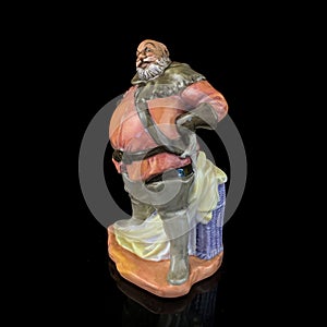 Ceramic statuette of a fat man on a black background.