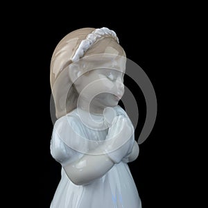 Ceramic statuette of a little girl isolated on black background.