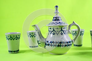 Ceramic teapot and cup on the green background