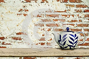 Ceramic teapot with old vintage brick wall background.